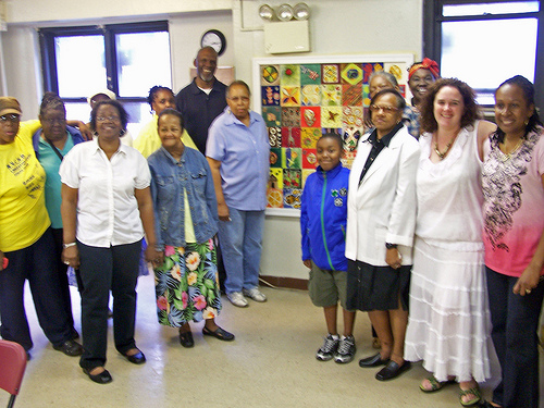 Langston Hughes Senior Center artists stand proudly in front of their mural.
